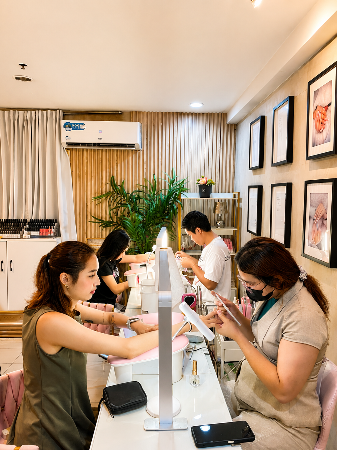 nail technicians at manicure stations with framed nail art on the wall, AyuriNails Beauty Lounge Makati